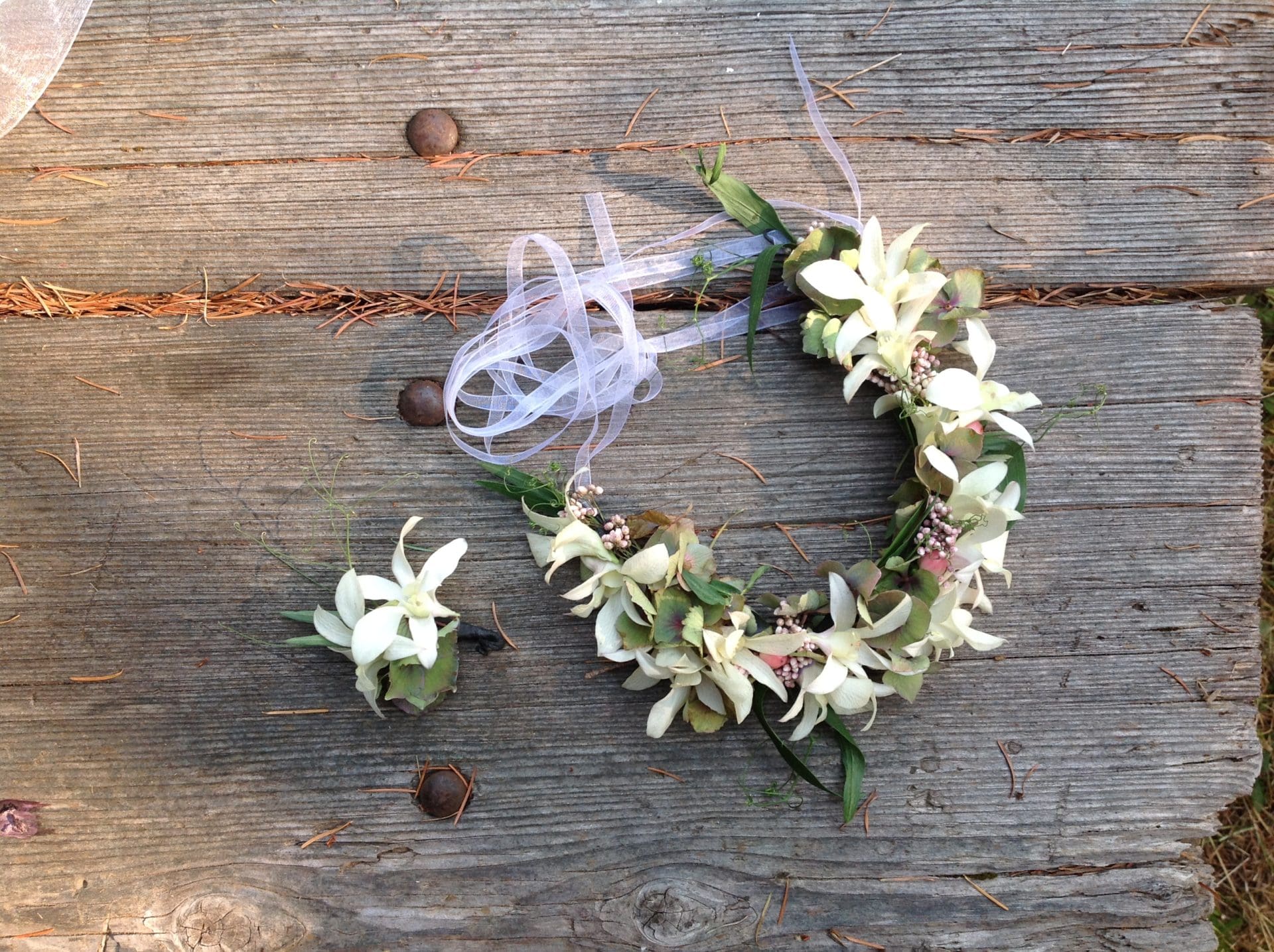 White flower crown and boutonniere on wood.