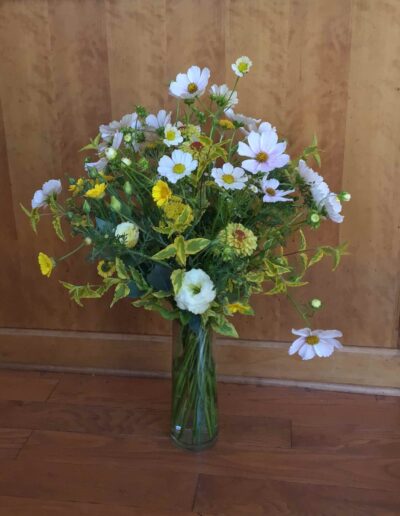A yellow & white country daisy bouquet with our own farm grown flowers in an elegant recycled glass vase.$80.00