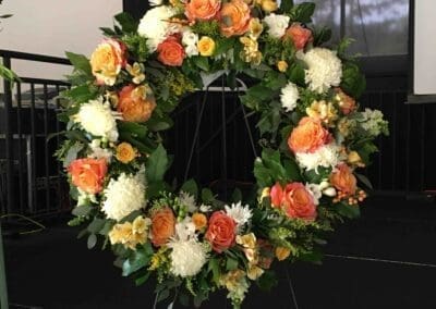 Floral wreath with orange roses and white flowers.