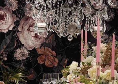 Floral wallpaper, crystal chandelier, dinner table setting.