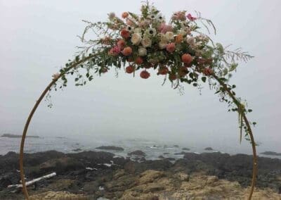 Floral archway overlooking rocky coast.