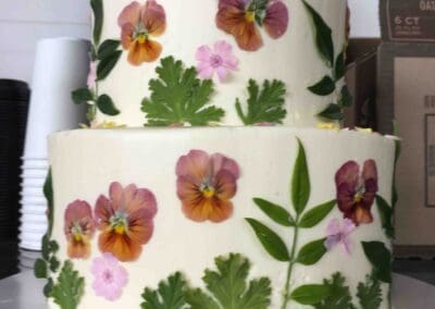 Two-tier cake with edible flowers and leaves.