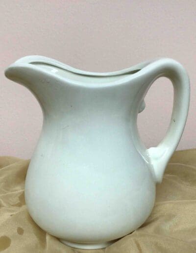 White ceramic pitcher on fabric.